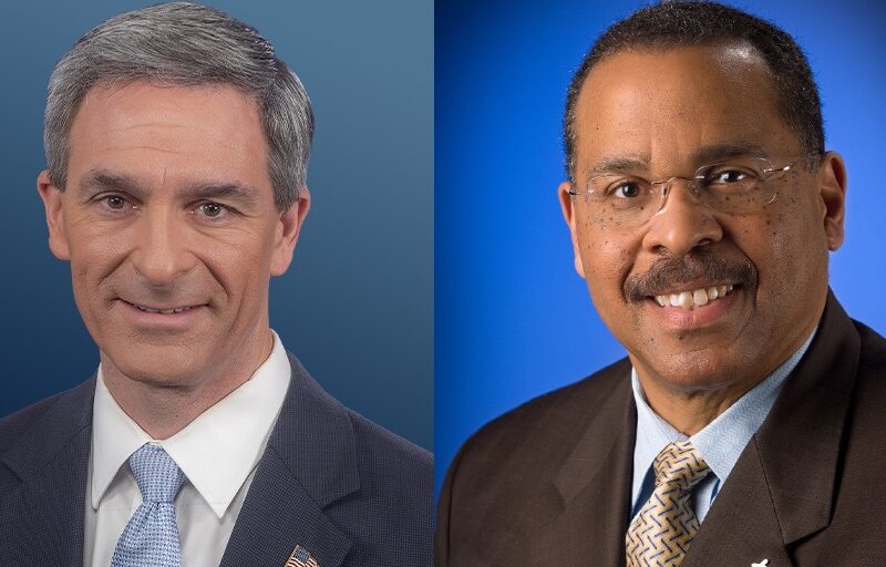 Two men in business attire, both smiling, are shown side by side against blue backgrounds. The man on the left has short gray hair and wears a suit and tie. The man on the right has short dark hair, glasses, and a patterned tie.